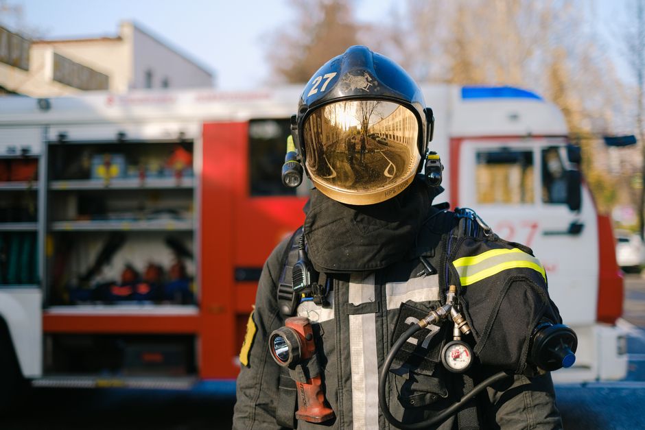 Firefighter in full protective gear standing in front of a fire truck