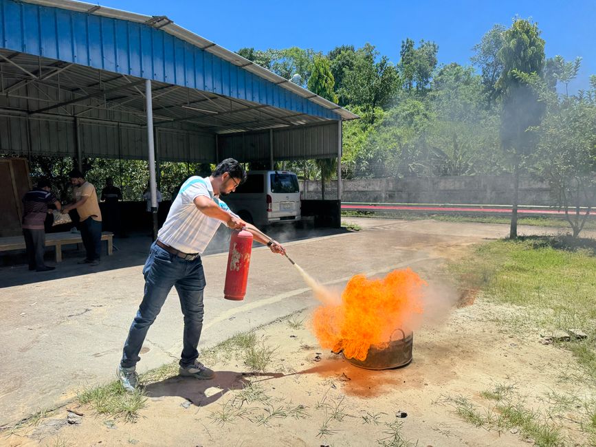 Trainee practicing live fire extinguisher use on a controlled training fire