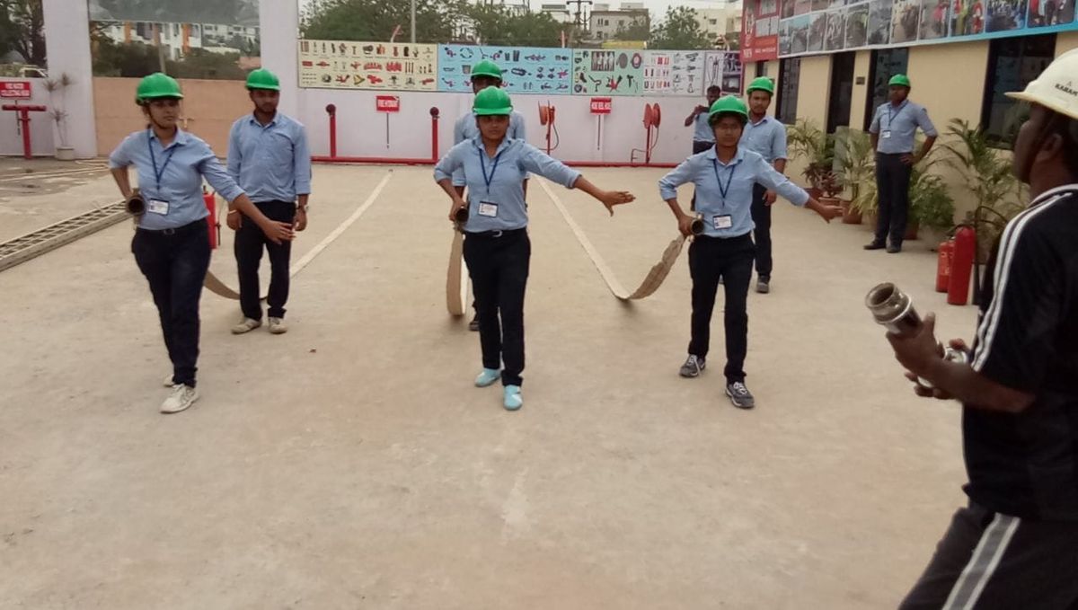 NIFS trainees in green helmets laying out fire hose lines during a practical exercise
